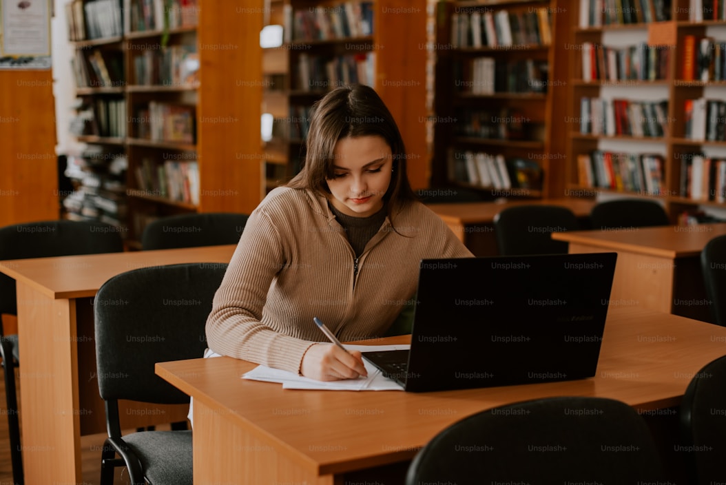 Student writing at a library desk
